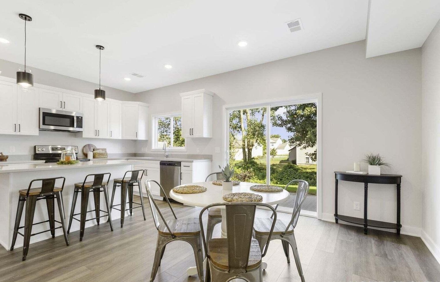 Open-concept kitchen and dining area at Signature Estates with white cabinetry, breakfast seating and large patio doors